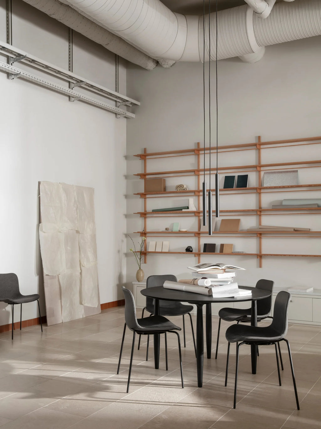 NORR11 Oku Round Dining Table, a modern, premium dark round dining table with a sculptural base. This elegant table is perfect for stylish, intimate dining spaces.