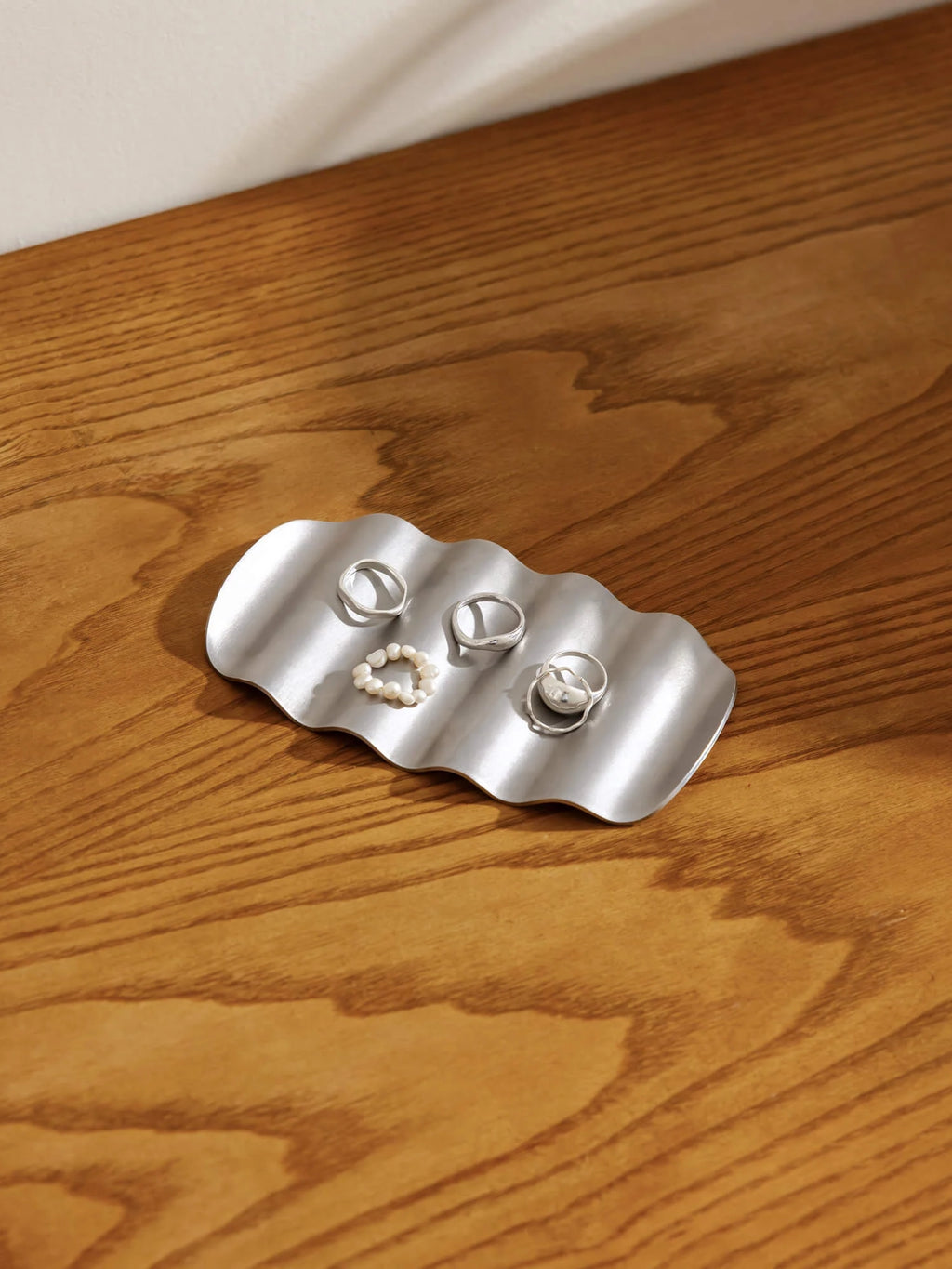 noo.ma Olbi Soap Dish, a modern minimalist wavy metal tray crafted from brushed silver stainless steel with an organic rippled surface and rounded edges. This contemporary decorative piece functions perfectly as a stylish soap dish for bathrooms or a versatile jewelry tray for vanity organization or entryway consoles.