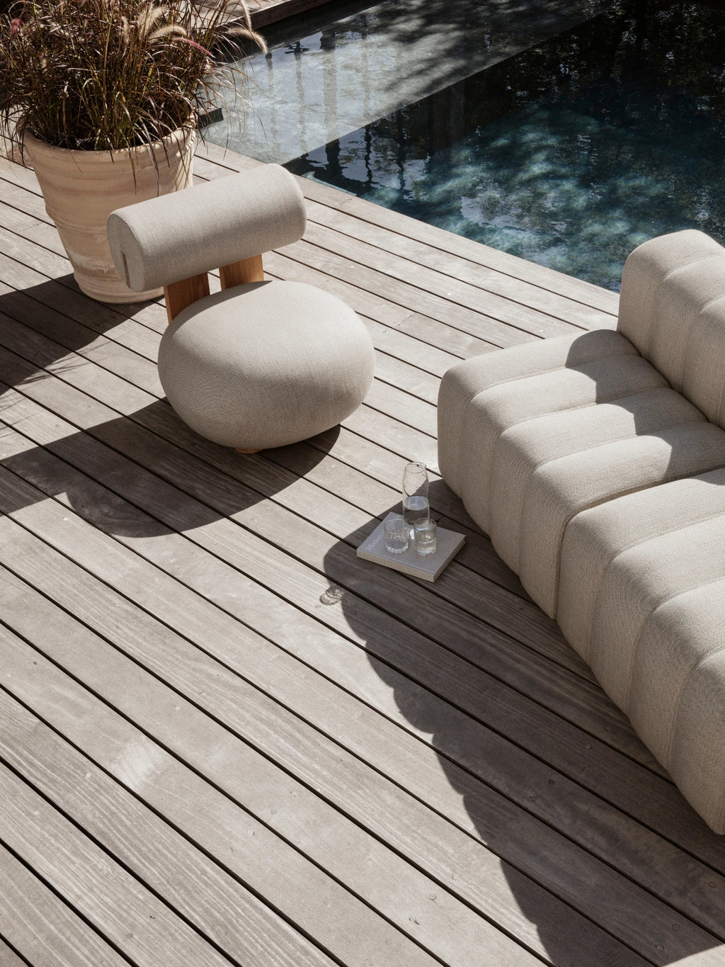 NORR11 Outdoor Hippo Lounge Chair, an organic modern outdoor lounge chair featuring a plush round seat and cylindrical backrest upholstered in light beige weather-resistant outdoor fabric with a subtle woven texture and a natural solid wood back support. This sculptural outdoor seating is perfect for minimalist patios, contemporary poolside areas, or stylish garden furniture setups.