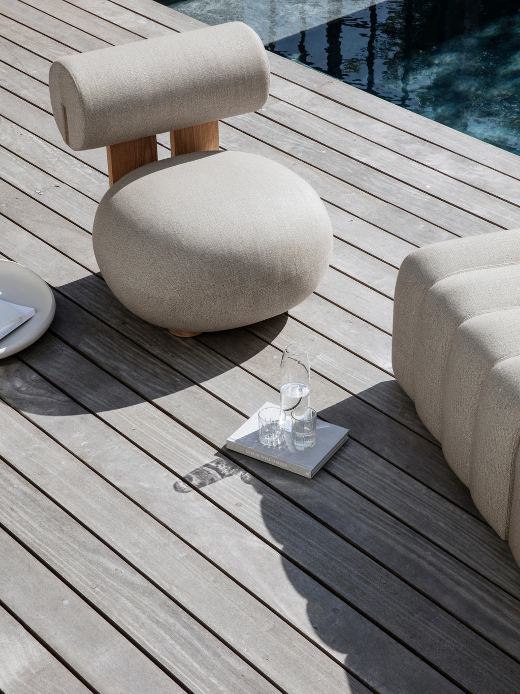 NORR11 Outdoor Hippo Lounge Chair, an organic modern outdoor lounge chair featuring a unique sculptural form with a rounded seat cushion and cylindrical backrest upholstered in light beige textured outdoor fabric.