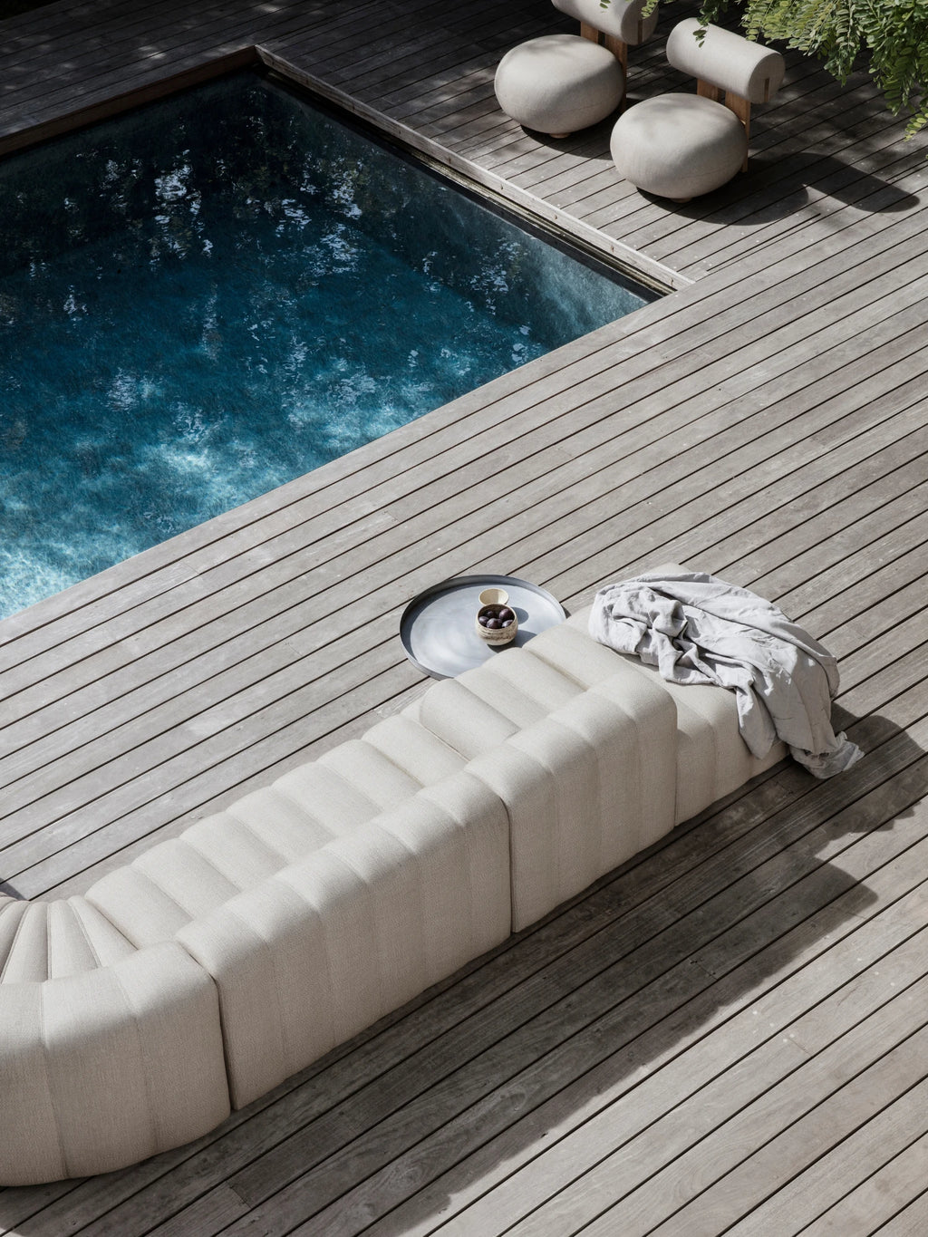 NORR11 Outdoor Hippo Lounge Chair, a modular curved outdoor lounge chair upholstered in a textured light beige outdoor fabric with distinct vertical ribbed channels, offering a plush and inviting organic modern aesthetic. This low-slung, contemporary design is perfect for creating stylish poolside lounging areas, minimalist patio seating, or a sophisticated outdoor living space.