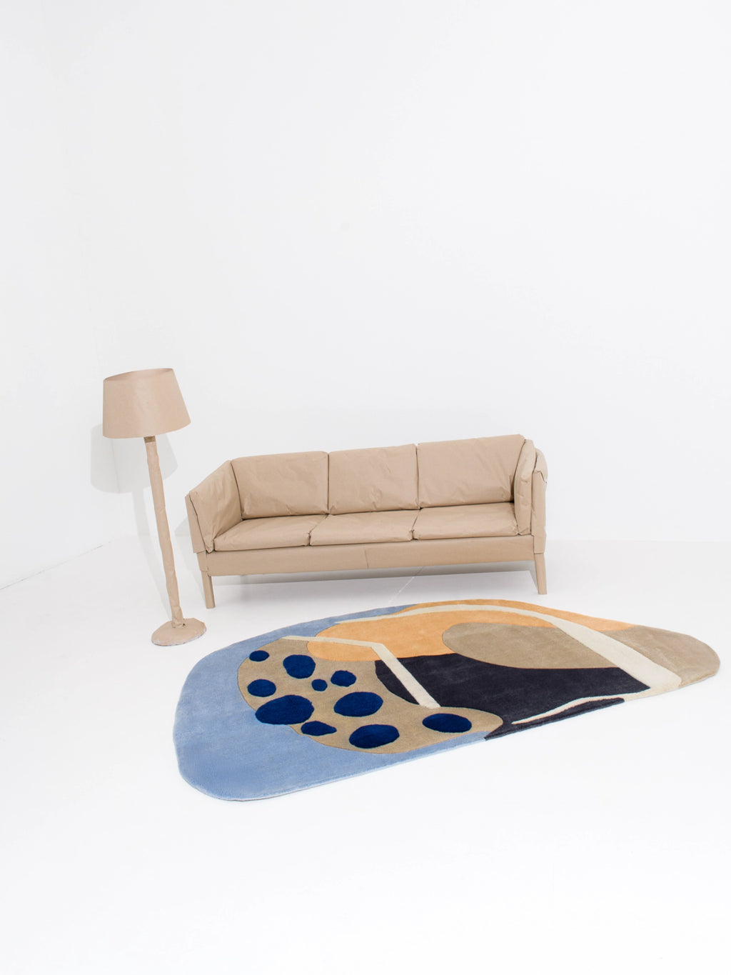Haus Üger Papillon Rug, a contemporary abstract area rug featuring an organic irregular shape and a plush soft pile in a vibrant palette of light blue, dark blue, warm beige, dark brown, and cream. This art-inspired floor rug showcases bold color blocking and playful polka dot accents, perfect for adding a statement to modern minimalist living rooms, creative office spaces, or stylish bedrooms.