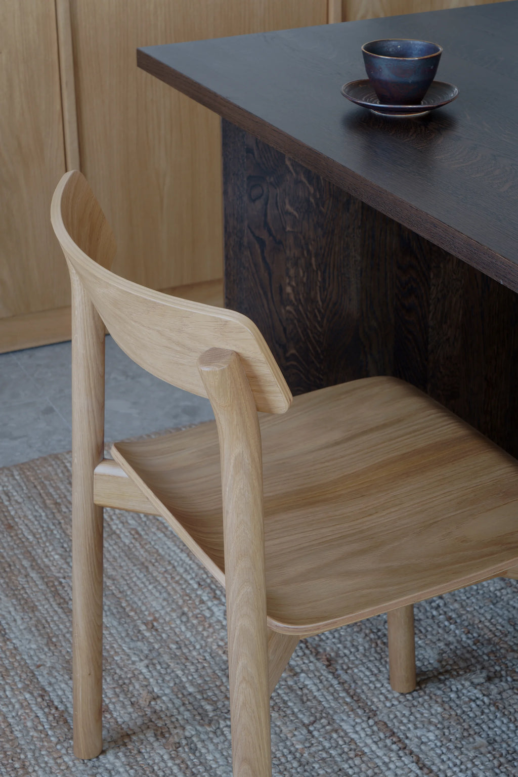 TAMO Arche Chair, natural light oak wood with a curved backrest and shaped seat, showing visible grain. A premium minimalist design, perfect for a modern dining space.