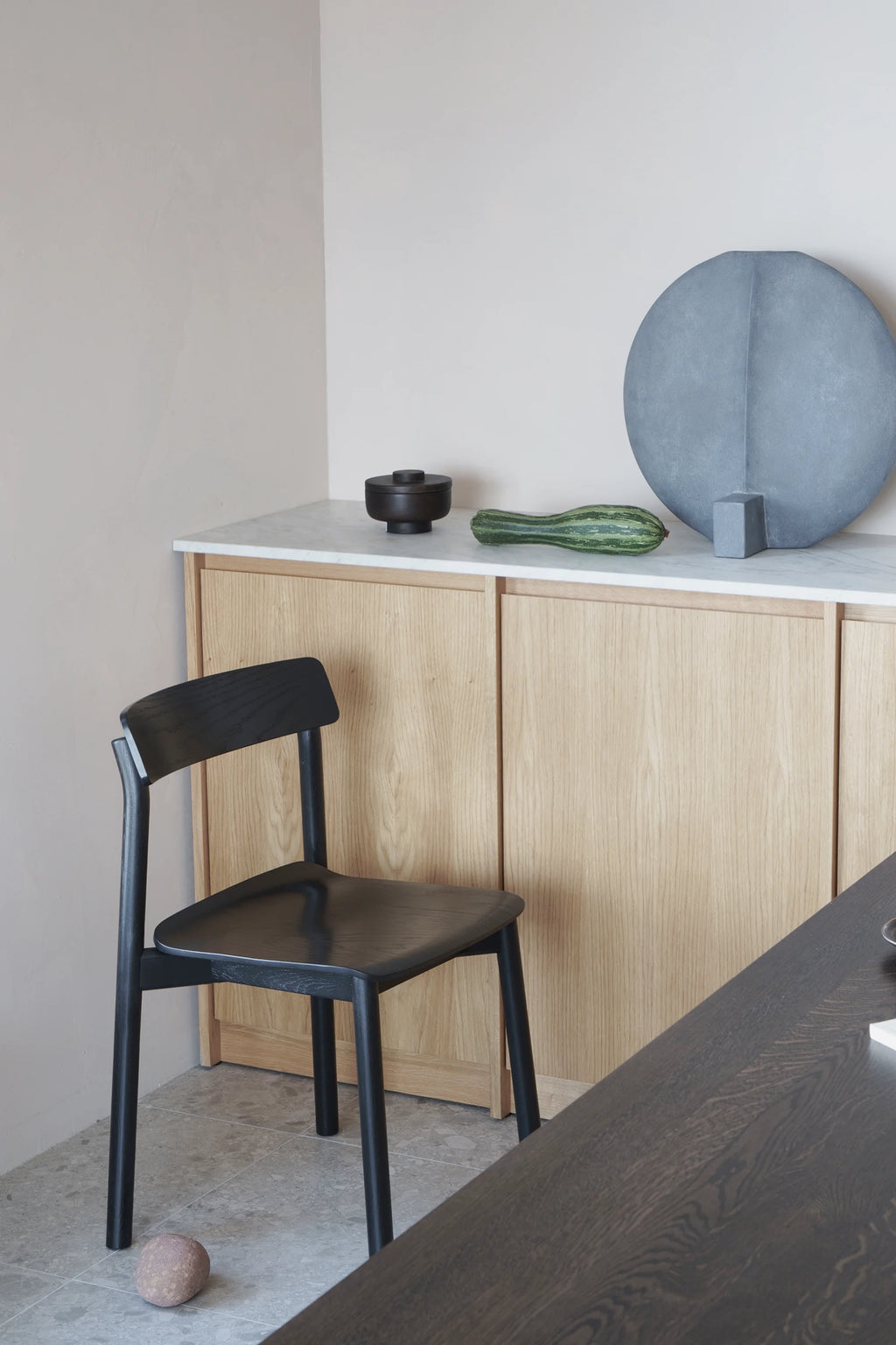 TAMO Arche Chair in a dark espresso finish, showcasing its minimalist wooden design with a gently curved backrest and seat, in a contemporary dining setting. Ideal for modern living spaces.