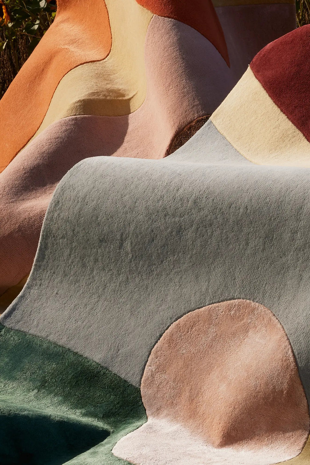 Layered Magical Garden Wool Rug, a plush, multi-colored abstract area rug featuring organic shapes in shades of sage green, light grey, terracotta, blush pink, and cream. Perfect for adding a moder...