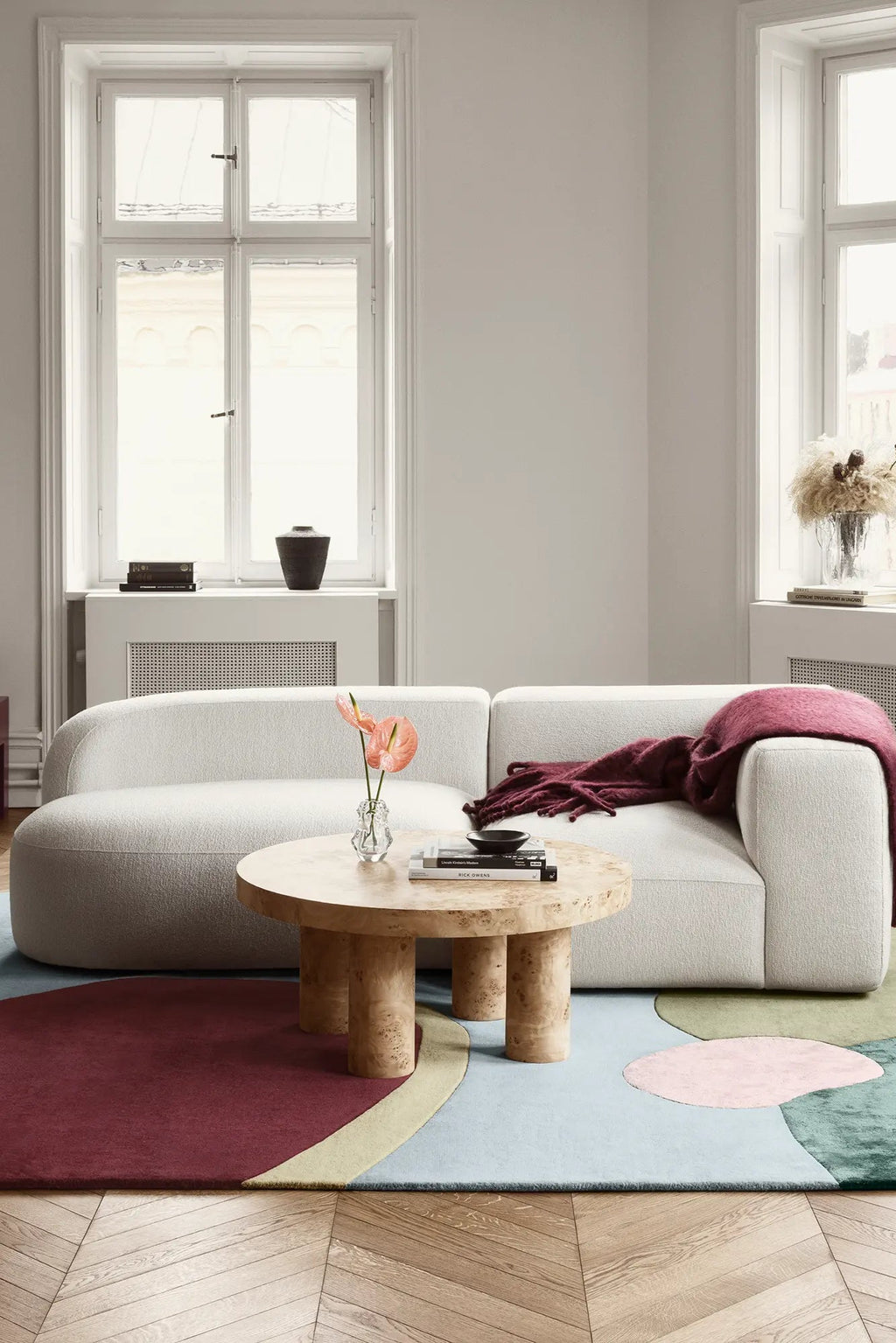 Layered Sleeping Flower Wool Rug, a modern abstract area rug featuring organic shapes in shades of maroon, light blue, pink, and green. Perfect for adding a vibrant, soft floor covering to a contem...