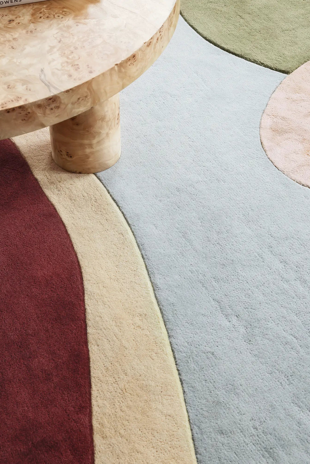 Layered Sleeping Flower Wool Rug, a luxurious modern area rug featuring abstract organic shapes in soft pastel blue, warm beige, deep burgundy, and sage green, with a plush wool pile texture. Perfe...