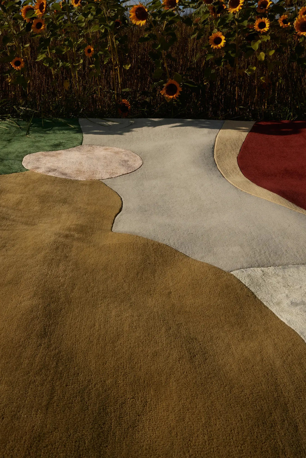 Layered Sleeping Flower Wool Rug, a modern abstract area rug featuring organic shapes in green, brown, light gray, and deep red. This plush wool floor covering adds a unique artistic touch to any l...