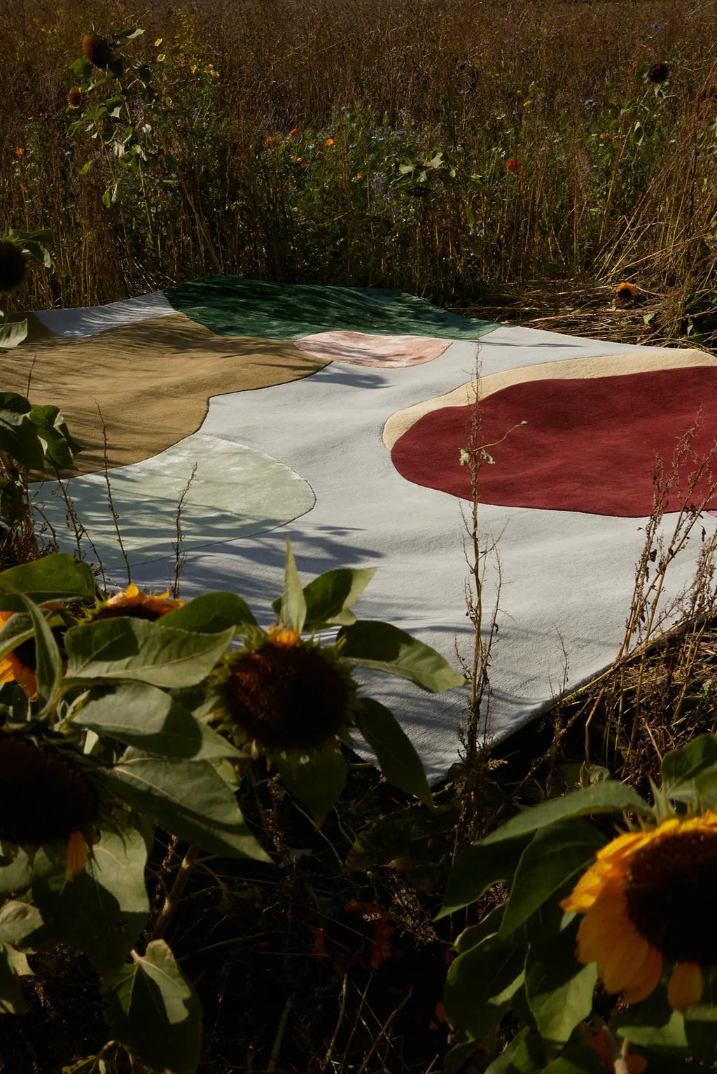 Layered Sleeping Flower Wool Rug, a modern art-inspired area rug with organic shapes in muted tones of green, rust, beige, and light grey. Perfect for adding a unique, soft texture to any contempor...