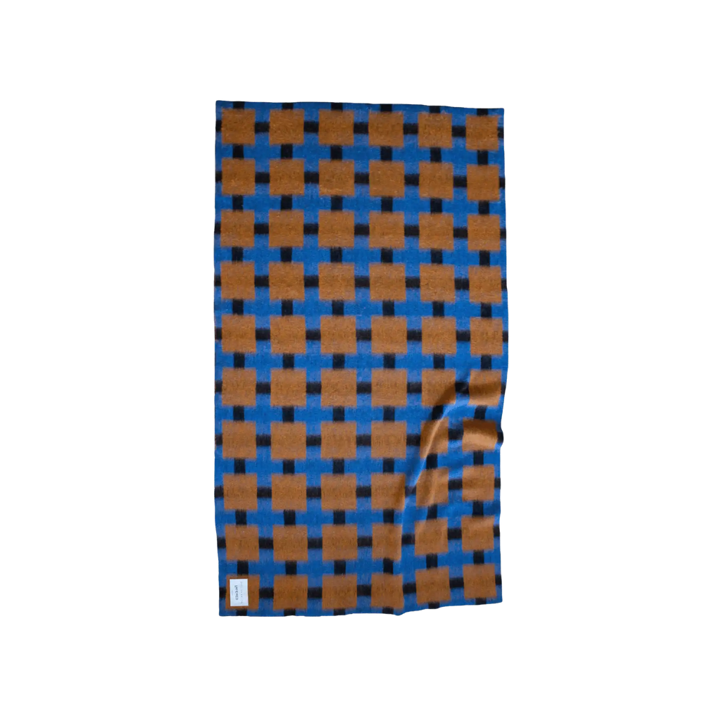 Layered Fall Foliage Oversized Blanket, a soft knit throw featuring a bold blue and brown checkerboard pattern with black interconnecting lines. Perfect for adding a cozy, stylish accent to any liv...