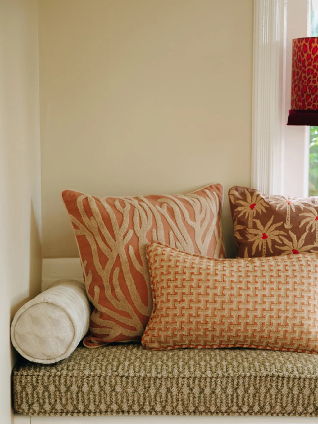 Palais Lauren Throw Pillow, a square decorative pillow featuring a vibrant coral and peach background with an intricate cream embroidered coral reef pattern, offering a rich texture and coastal charm. This tropical accent pillow is perfect for adding a touch of bohemian style to a living room sofa, bedroom decor, or window seat.