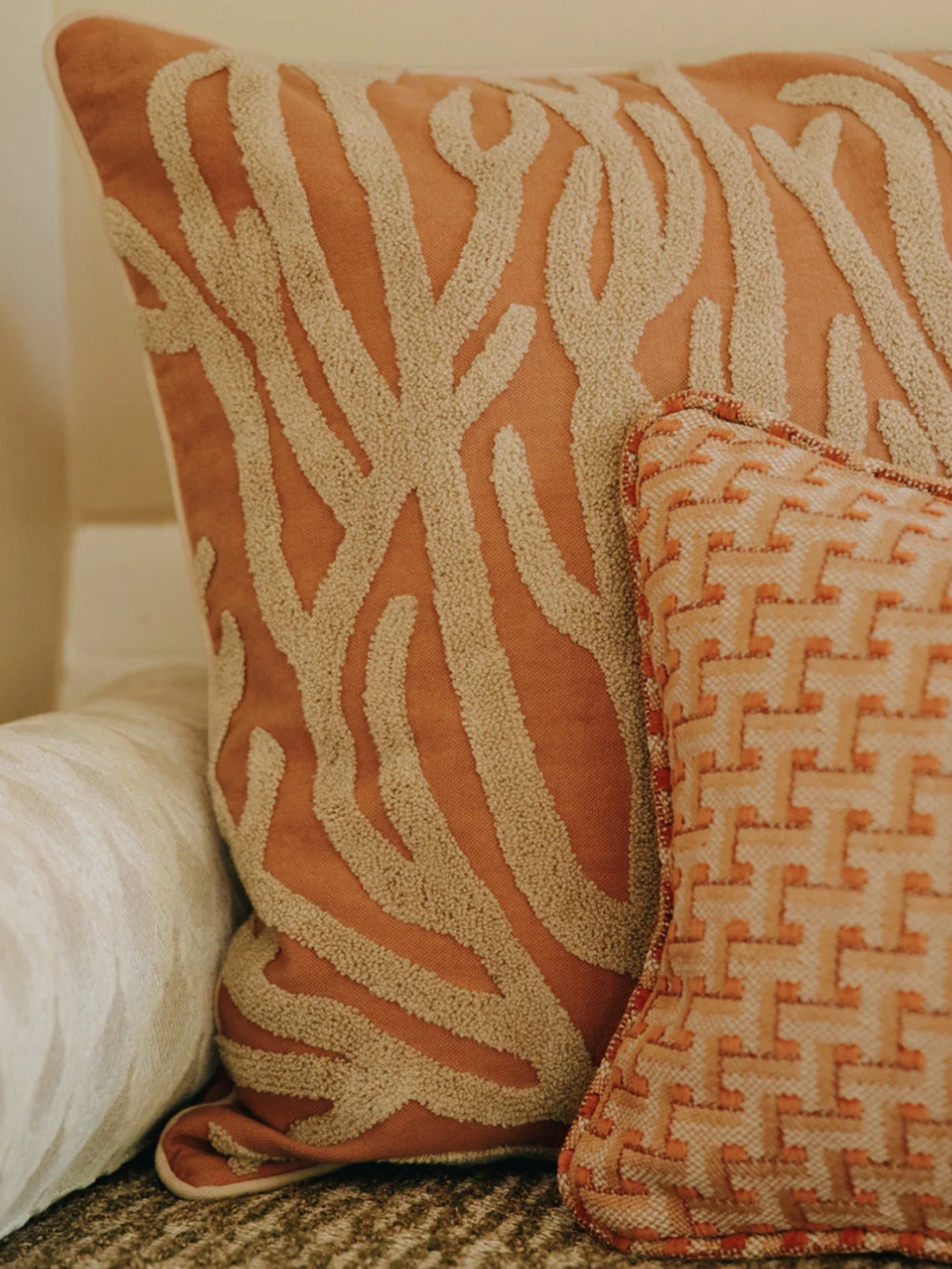 Palais Lauren Throw Pillow, a square burnt orange decorative cushion featuring a striking cream bouclé textured organic pattern that evokes natural coral or abstract branches, crafted from a soft cotton blend fabric.