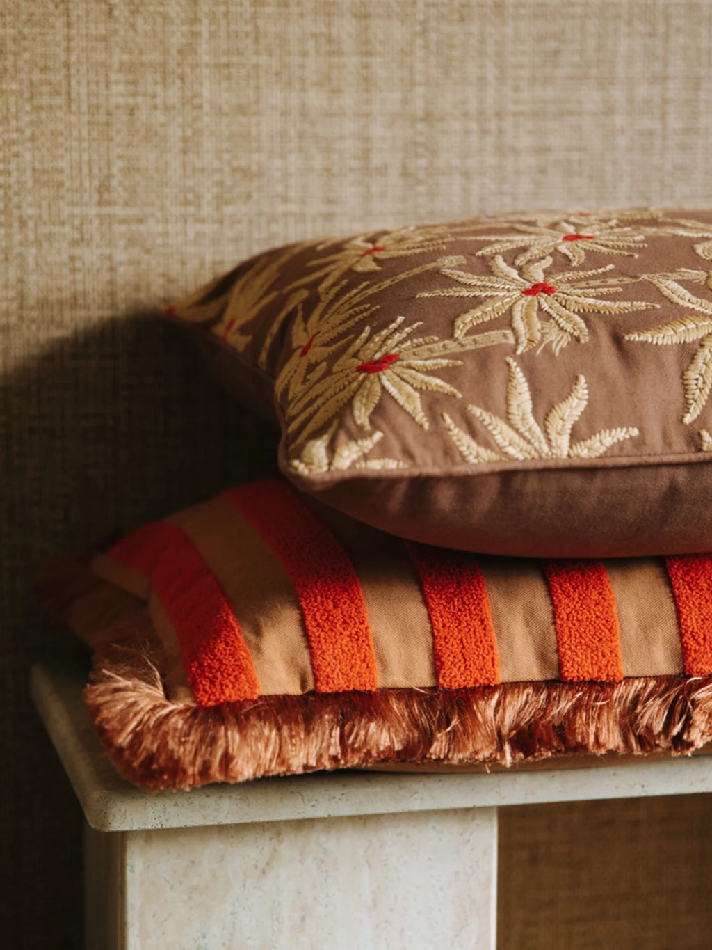 Palais Jackie Throw Pillow, a vibrant bohemian decorative cushion featuring bold orange tufted stripes on a warm tan base fabric, finished with playful matching orange fringe along the edges.