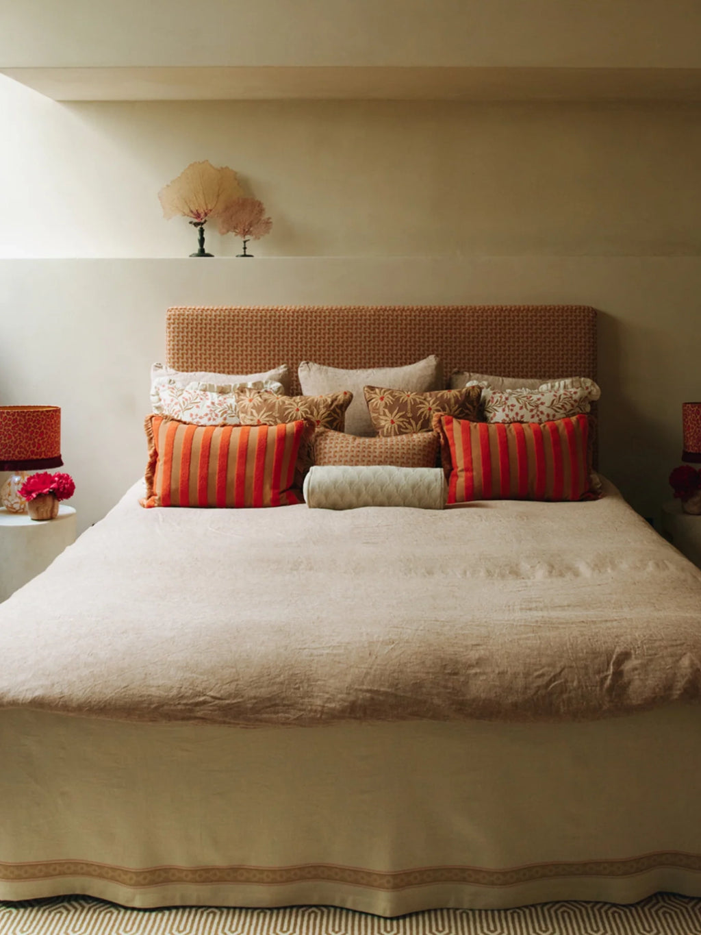 Palais Jackie Throw Pillow, a vibrant rectangular lumbar pillow featuring bold orange-red and warm tan vertical stripes with a textured woven fabric and fringed edges. This eye-catching accent cushion brings a touch of eclectic boho charm to any space. Perfect for bed styling in a rustic Mediterranean bedroom or adding a pop of color to a living room sofa.