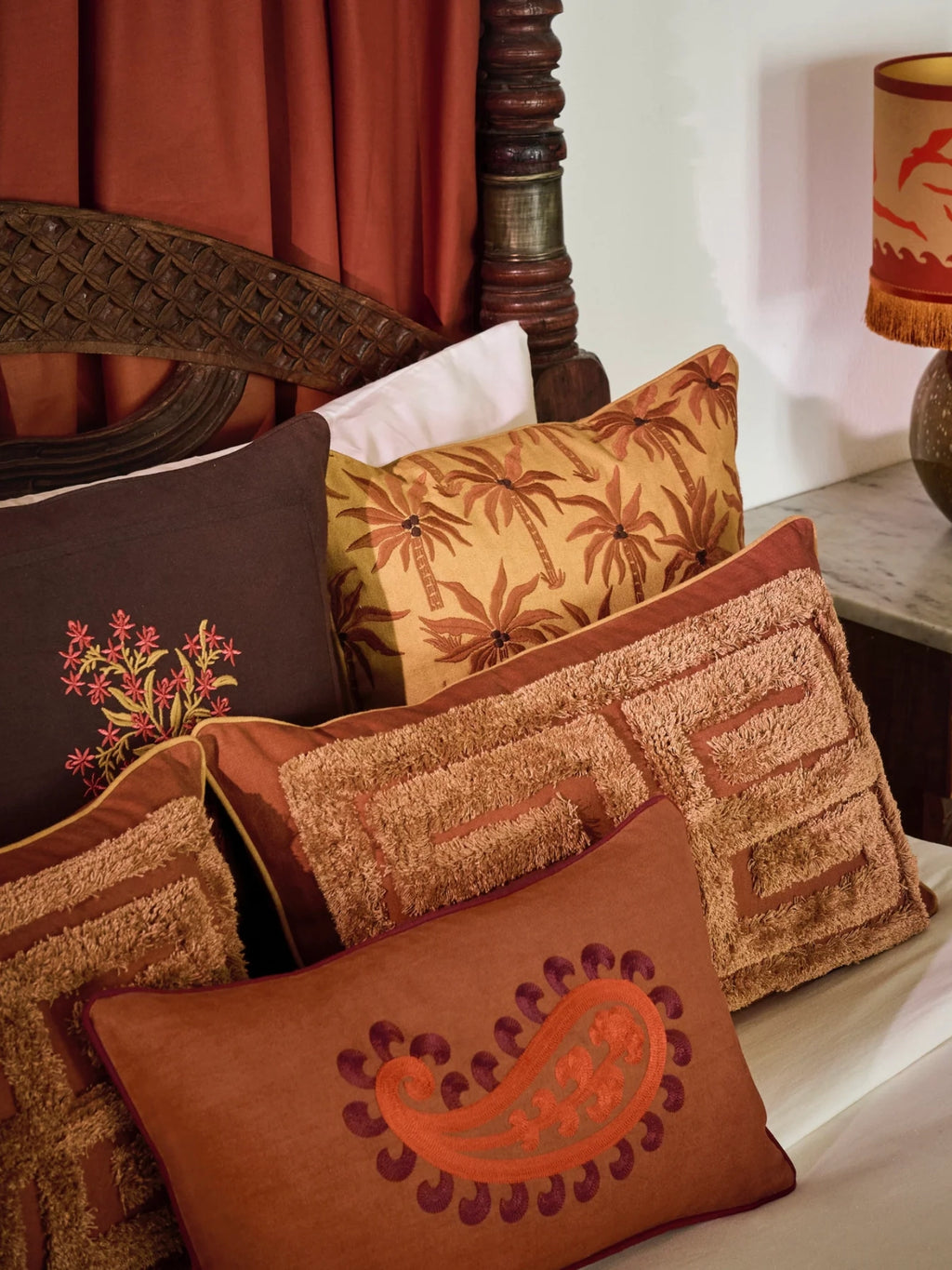 Palais Double Sided Siena Throw Pillow, a rectangular bohemian accent cushion featuring intricate orange and burgundy paisley embroidery on a rich terracotta-colored fabric, with a coordinating solid reverse for versatile styling.