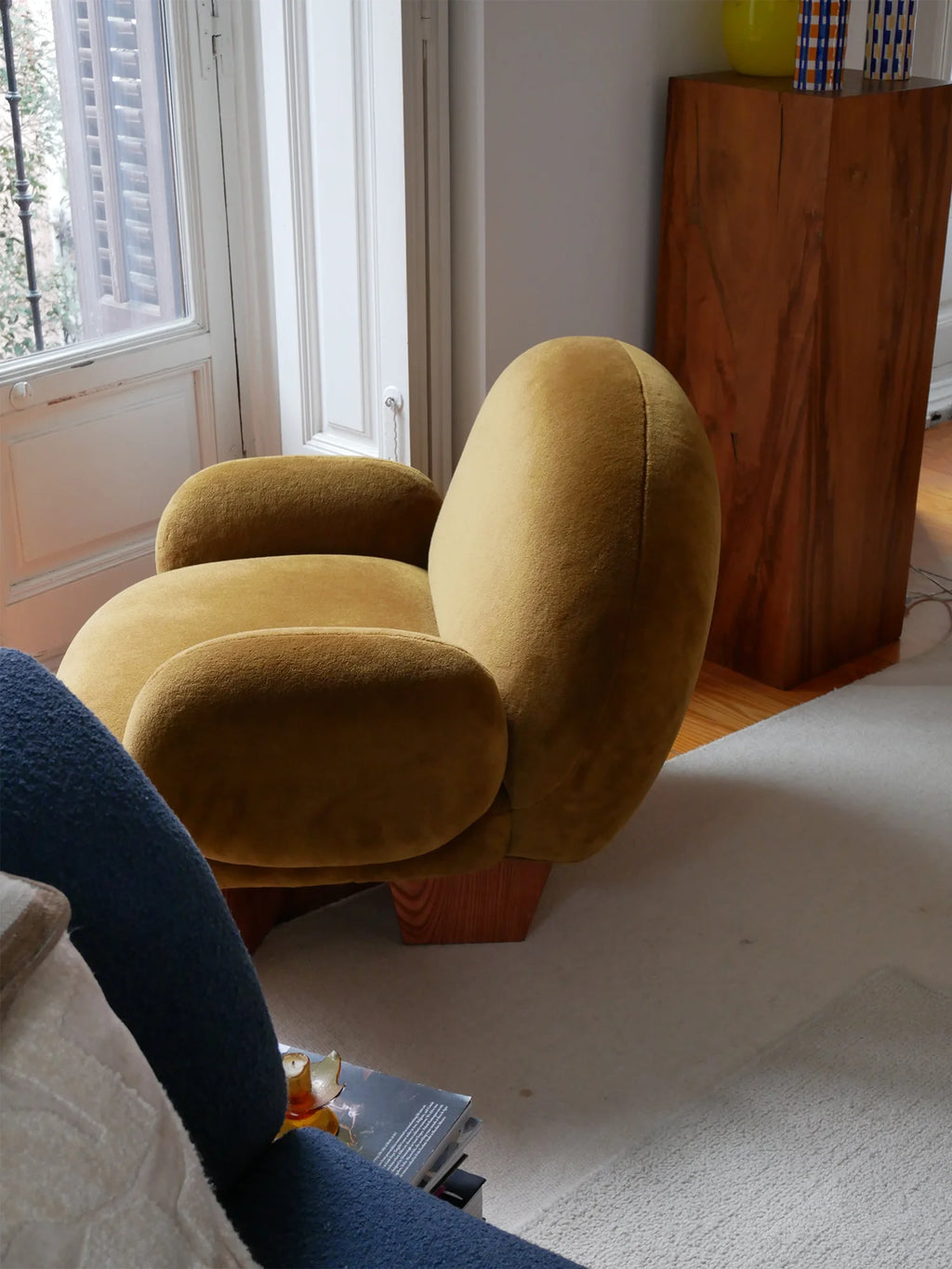 Heaps & Woods Paloma Velvet Lounge Chair, a contemporary organic modern lounge chair upholstered in rich mustard yellow velvet, featuring a sculptural, bulbous silhouette with plush deep seating. This inviting accent chair rests on a sturdy natural solid wood block base, offering a warm contrast to its soft texture. Ideal for a stylish living room, cozy reading nook, or modern bedroom.