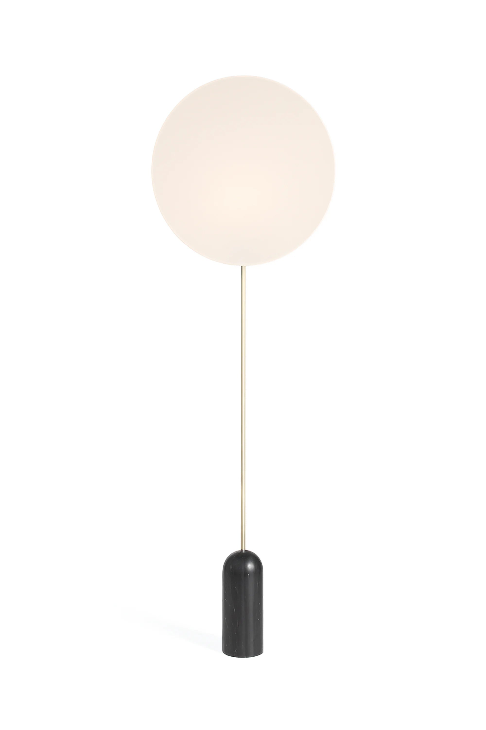 Floor lamp with a round white shade and black base on a white background