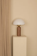 Table lamp with wooden base and white shade against a beige wall