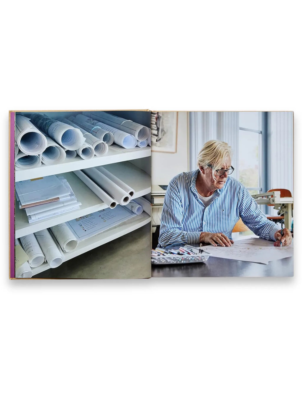 Book Piet Oudolf at Work, an open book displaying two images: on the left, white shelves filled with rolled-up blueprints and design plans, and on the right, Piet Oudolf himself, a man with blonde hair and glasses wearing a blue striped shirt, intently drawing on a large white paper at a wooden table in a well-lit studio. This comprehensive gardening book offers insight into the creative process of a renowned landscape designer.