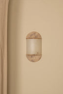 Round wall sconce with marble-like finish on a beige wall.