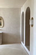 Modern bathroom with beige walls, a white archway, and a mirror.