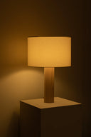 Table lamp with wooden base and beige shade on a dark background