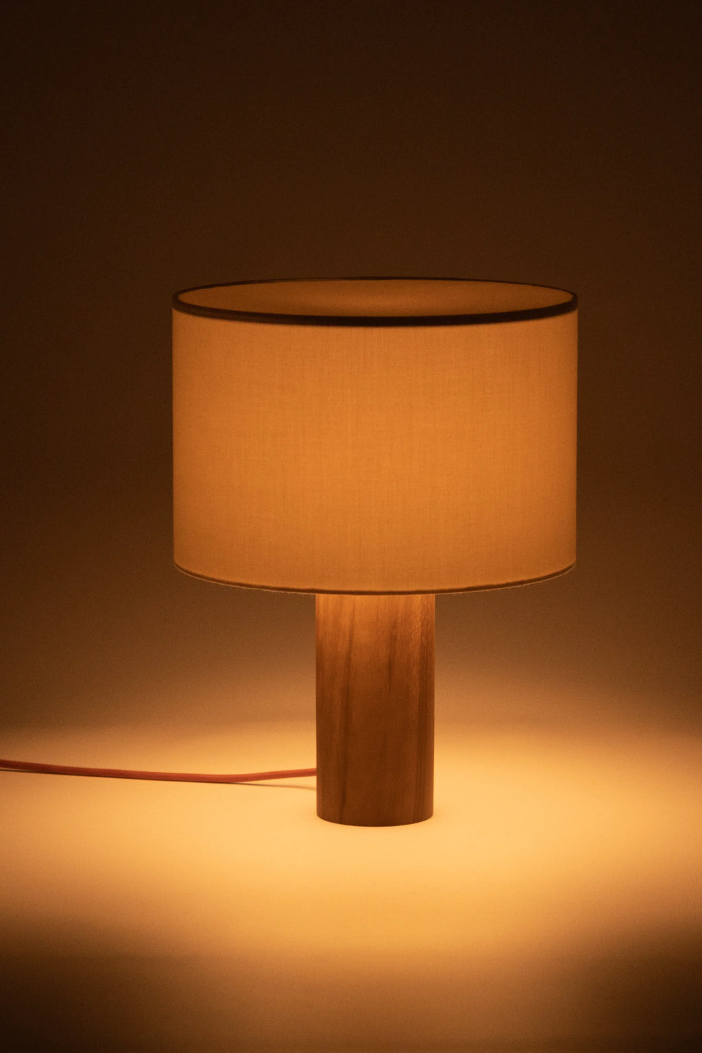 Table lamp with wooden base and beige fabric shade on a dark background