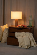 Napkin on a wooden surface with a lamp and books in the background