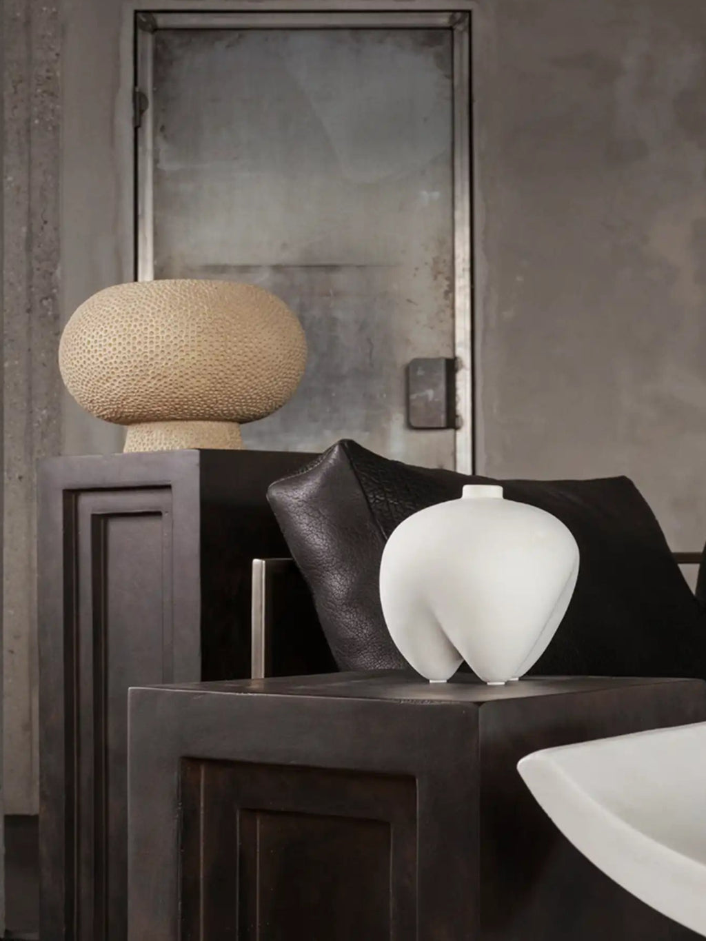 101 CPH Kabin Vase - Shisen. A white, organic-shaped ceramic vase with a matte finish, displayed on a dark wooden table in a contemporary setting. This handcrafted luxury decor piece creates visual interest.