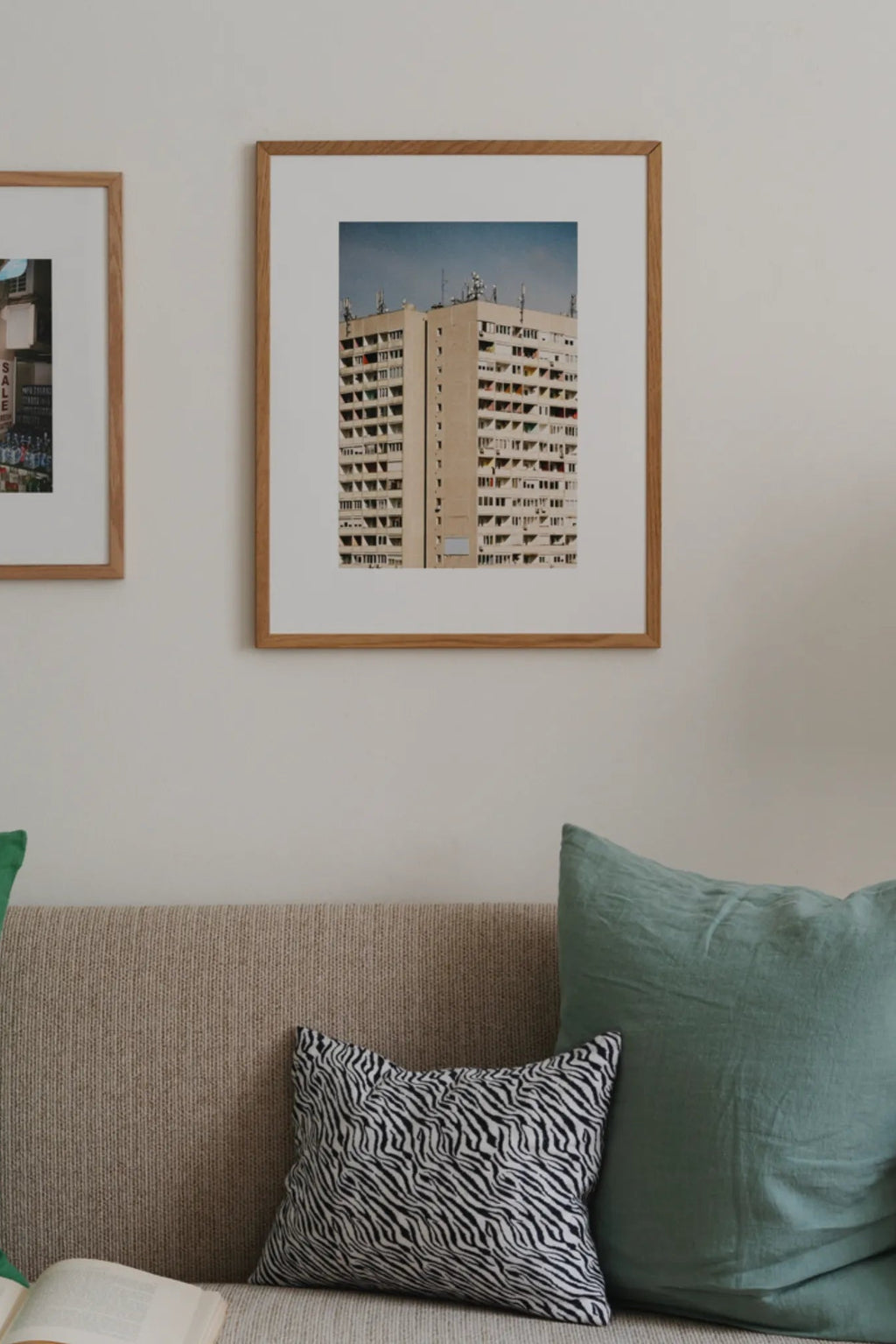 The Poster Club Block O’Clock, an architectural photography print featuring a towering brutalist-style apartment building in beige tones against a clear blue sky, capturing an urban landscape with intricate window details. This contemporary wall art is presented with a crisp white mat and a light natural oak frame. Ideal for modern minimalist gallery walls or as a statement piece in urban-inspired living rooms and home offices.