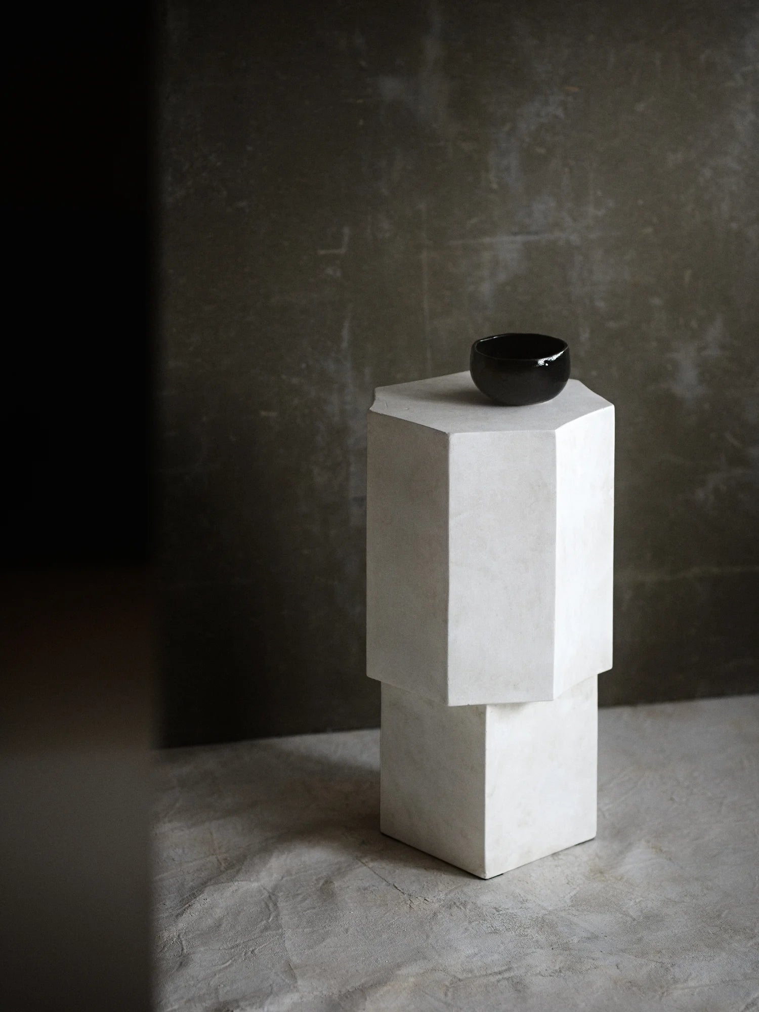 NORR11 Quartz Side Table, a modern hexagonal side table crafted from pale, textured material. This elegant piece features a stacked design and a dark accent bowl on top. Perfect for adding a touch of understated luxury to contemporary living spaces.