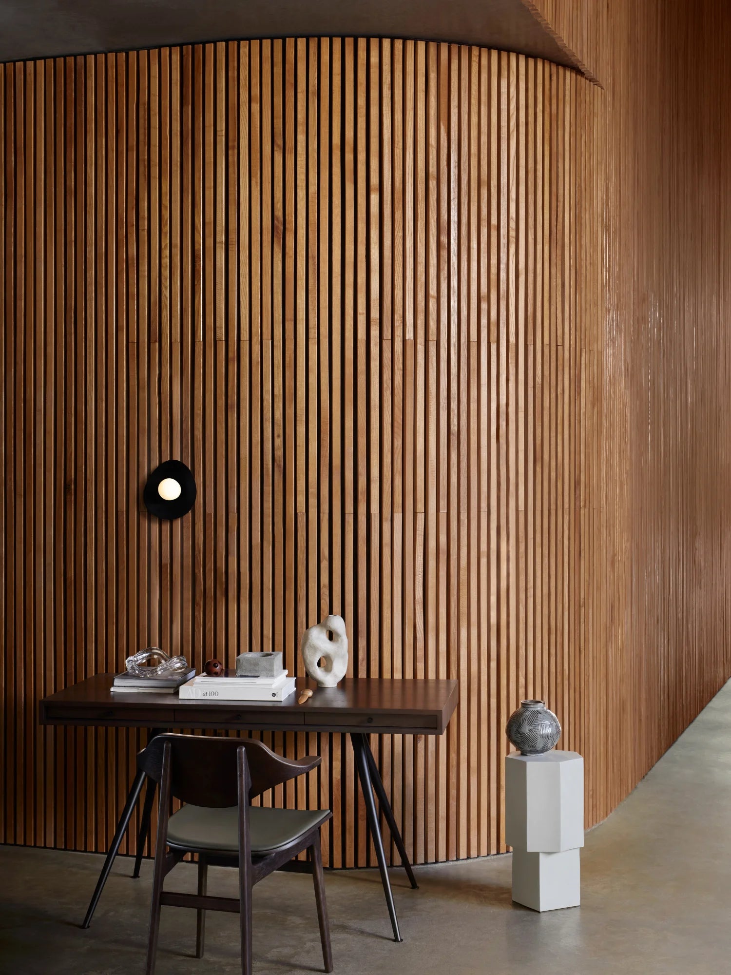 NORR11 Quartz Side Table, a modern, elegant side table crafted with a rich wooden slatted wall backdrop and a dark wood table. This stylish piece is perfect for adding a touch of luxury to contemporary living spaces.