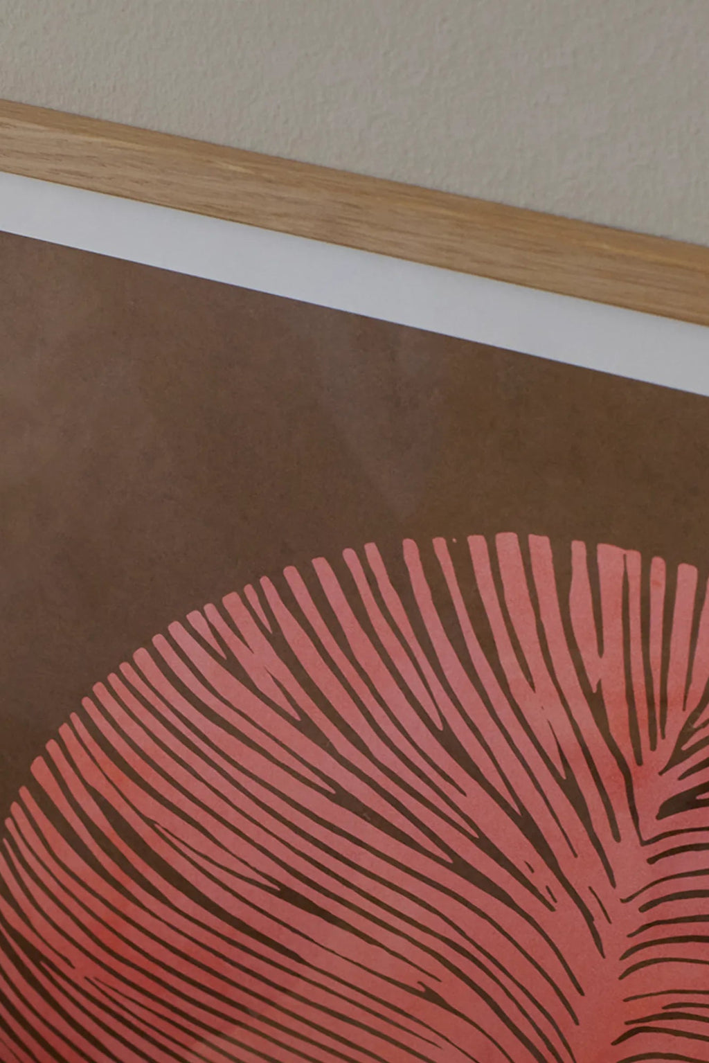 The Poster Club Pink Lagoon, a contemporary abstract art print featuring a large organic leaf-like graphic in muted coral pink with fine lines against a deep brown background, framed in natural oak with a white mat. This minimalist botanical poster is ideal for organic modern living rooms, minimalist bedrooms, or contemporary gallery walls.