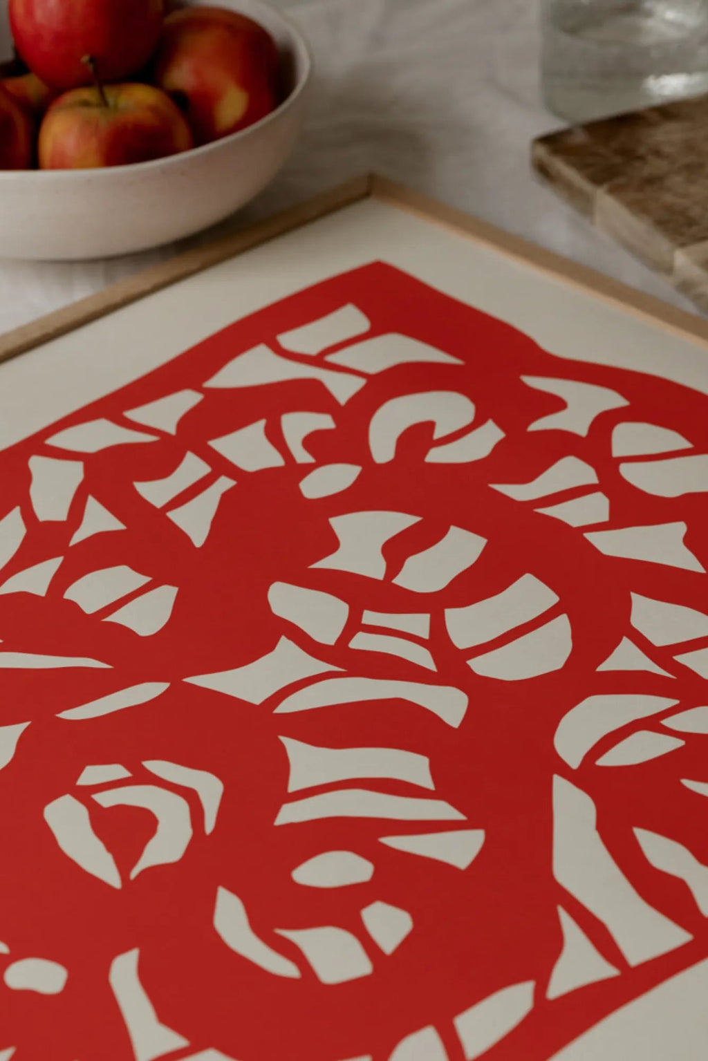 The Poster Club Root no. 04, a vibrant red abstract art print featuring bold organic cut-out shapes against a soft cream background, framed in a light natural oak frame. This modern minimalist poster is perfect for Scandinavian living rooms, contemporary bedrooms, or creating a striking gallery wall accent.