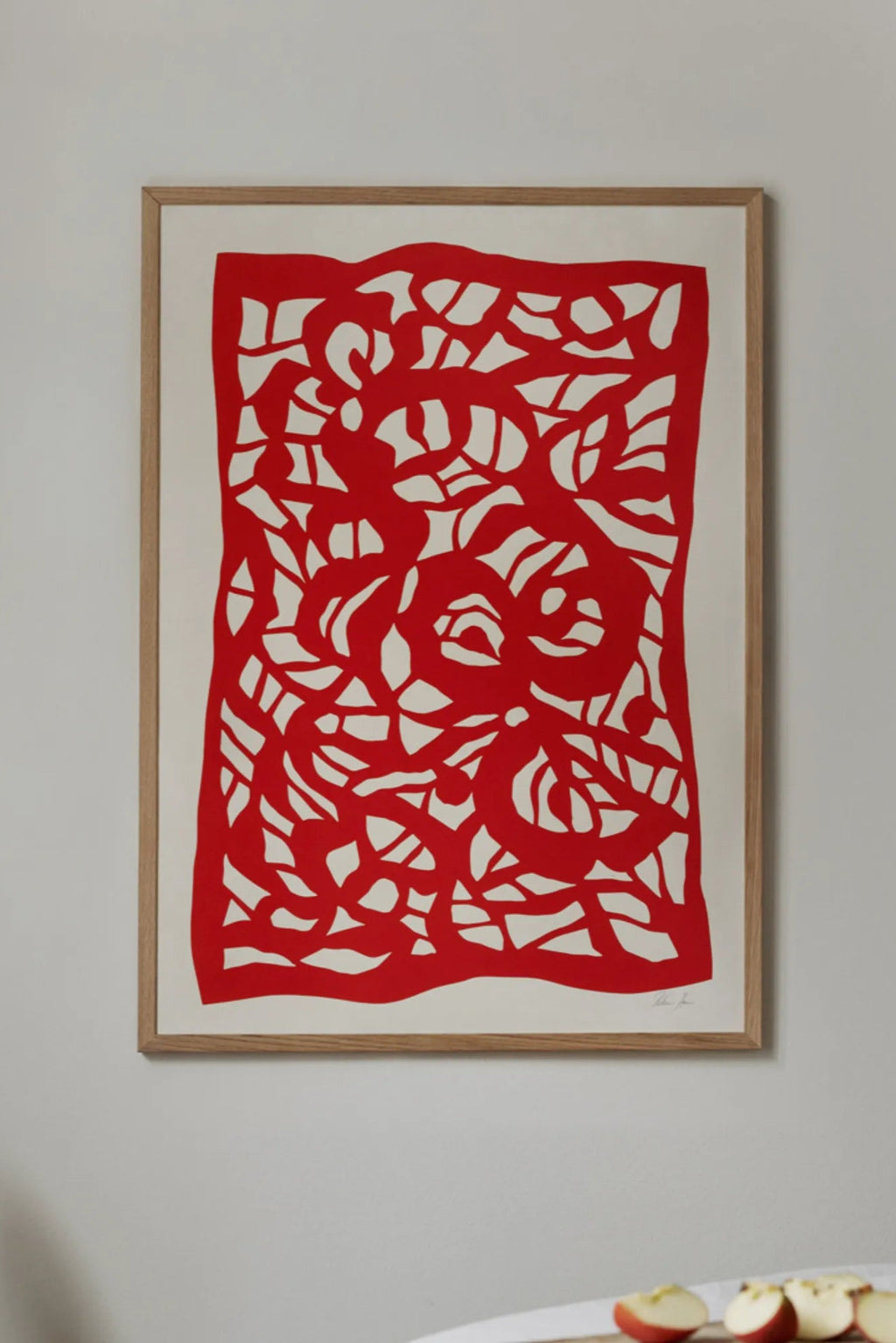 The Poster Club Root no. 04, a vibrant red abstract art print showcasing intricate organic botanical shapes in a striking paper-cut style, set against a soft cream background and framed in a light natural.