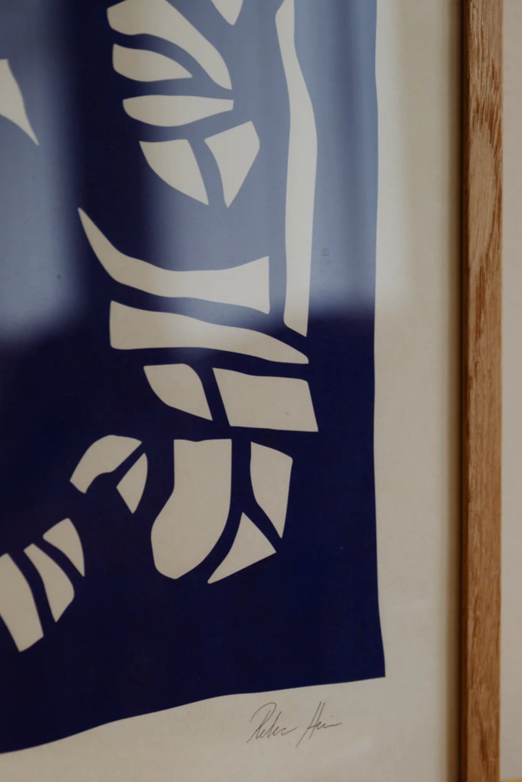 The Poster Club Root no. 03, a modern abstract art print showcasing bold organic cut-out shapes in deep indigo blue against an off-white background, framed in natural oak with a crisp white mat. This minimalist poster is ideal for contemporary gallery walls, Scandinavian living rooms, or modern bedroom decor.