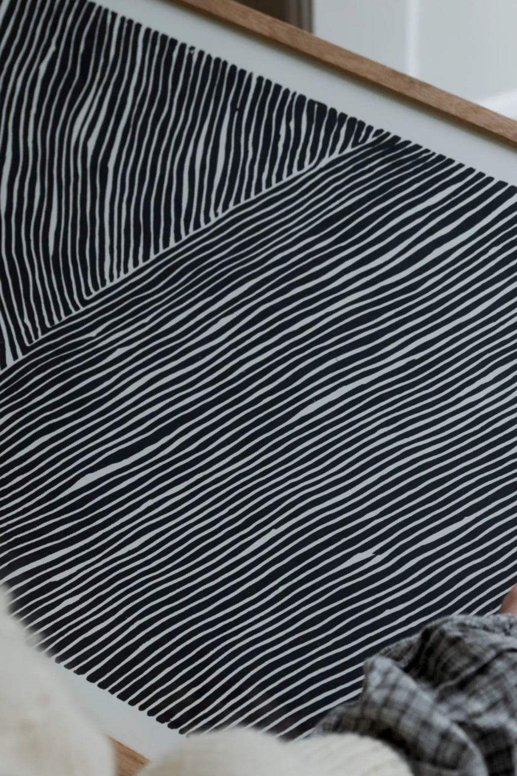 The Poster Club The Line no. 01, a minimalist abstract art print featuring hand-drawn black lines on a crisp white background, divided into two sections with contrasting vertical and diagonal patterns, framed in a light natural oak frame. This graphic black and white poster is perfect for contemporary gallery walls, Scandinavian living rooms, or modern minimalist bedrooms.