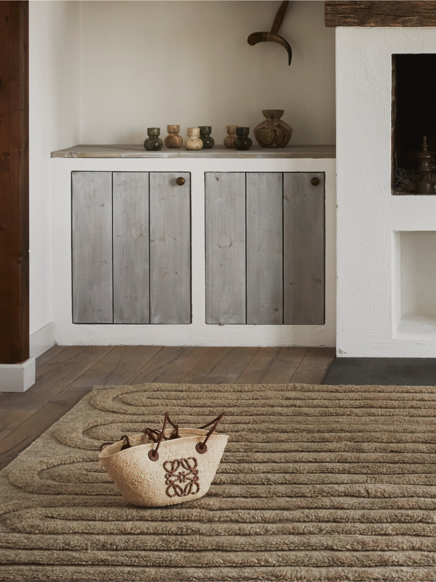 Tinted Objects Riklund Wool Rug, a plush, textured area rug in a warm, natural beige color with an intriguing raised, swirling pattern. This luxurious wool rug is perfect for adding warmth and sophisticated style to a modern living room or bedroom.