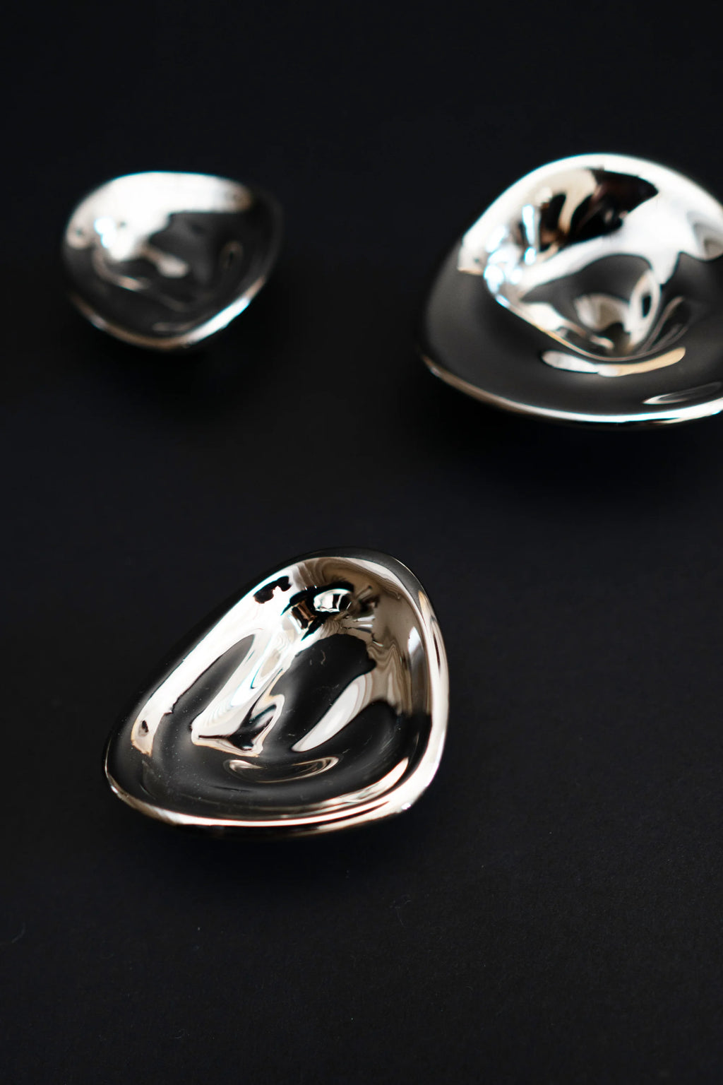 Hein Studio Ripple Hook/Knob array featuring three unique polished silver-tone, organically shaped metal pieces on a dark background. These luxury designer accent pieces are perfect for modern interiors.