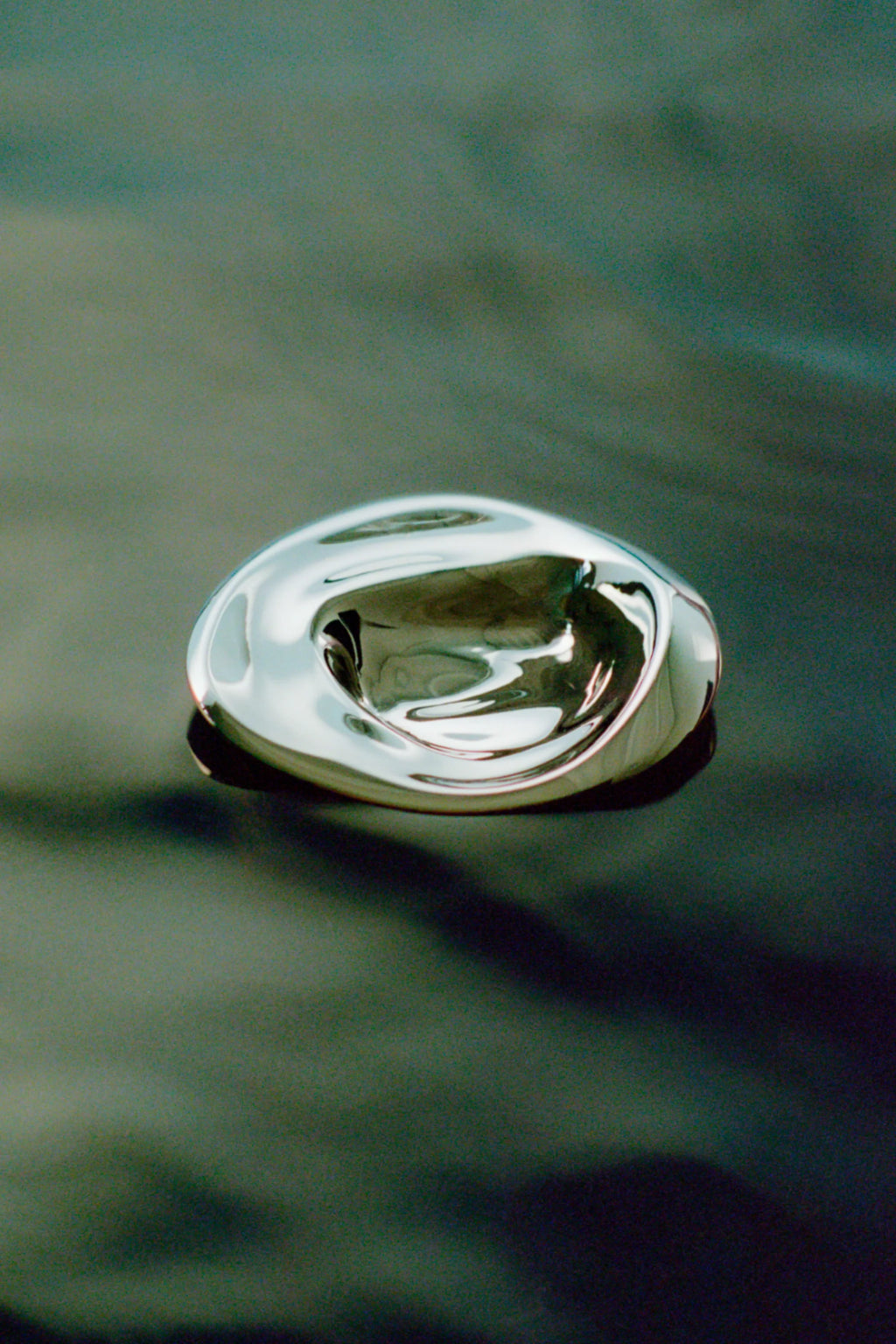 Hein Studio Ripple Hook/Knob: a shiny, polished silver metal, organic-shaped decorative knob or hook with a fluid, ripple-like surface on a dark gray background. This premium artistic hardware provides a sophisticated accent.