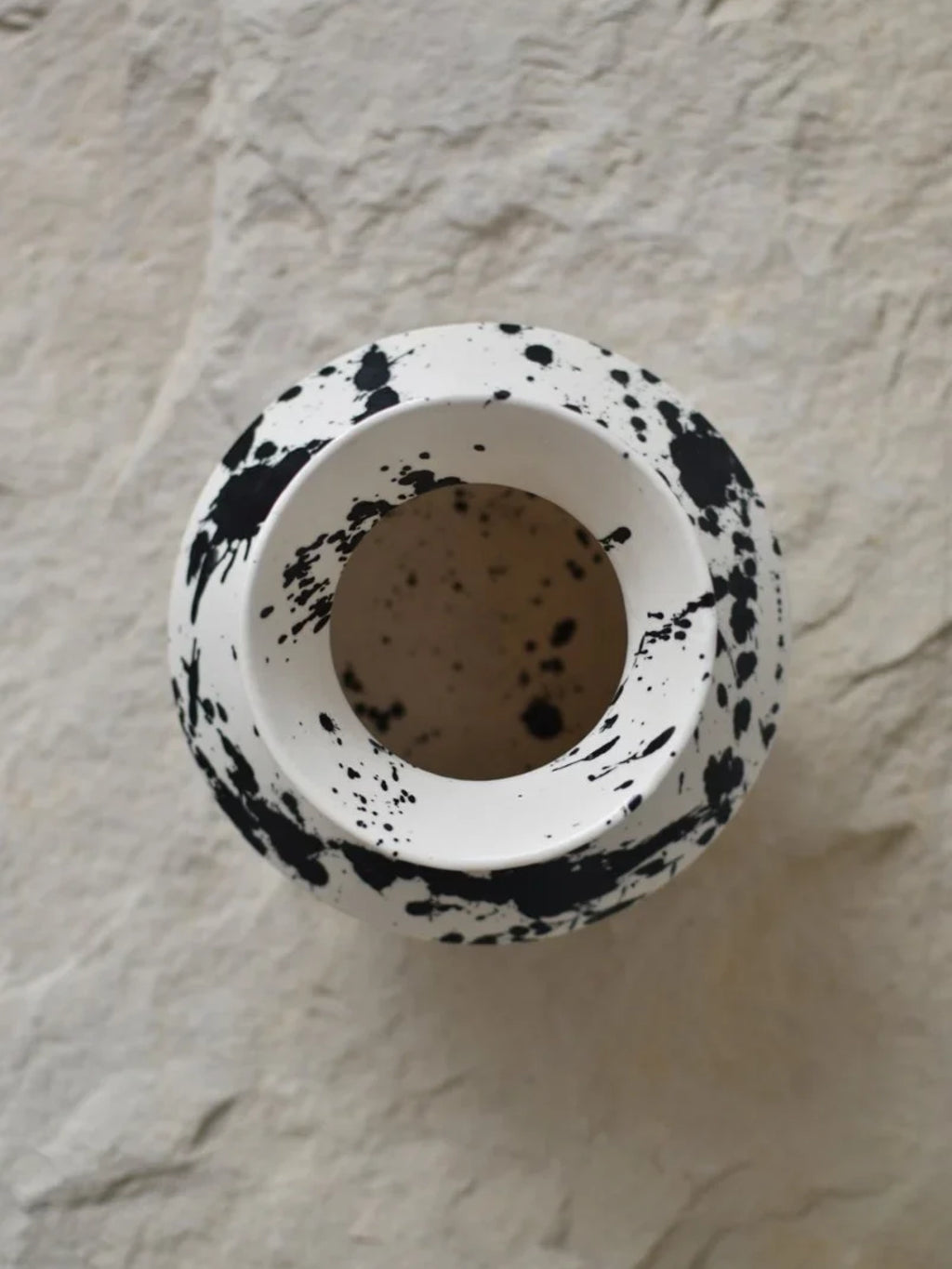 OWO Ceramics x That Cool Living Rock Vase I, a handcrafted ceramic vase with a white base and an abstract black splatter pattern. This modern and elegant vase adds a stylish touch to any home decor.