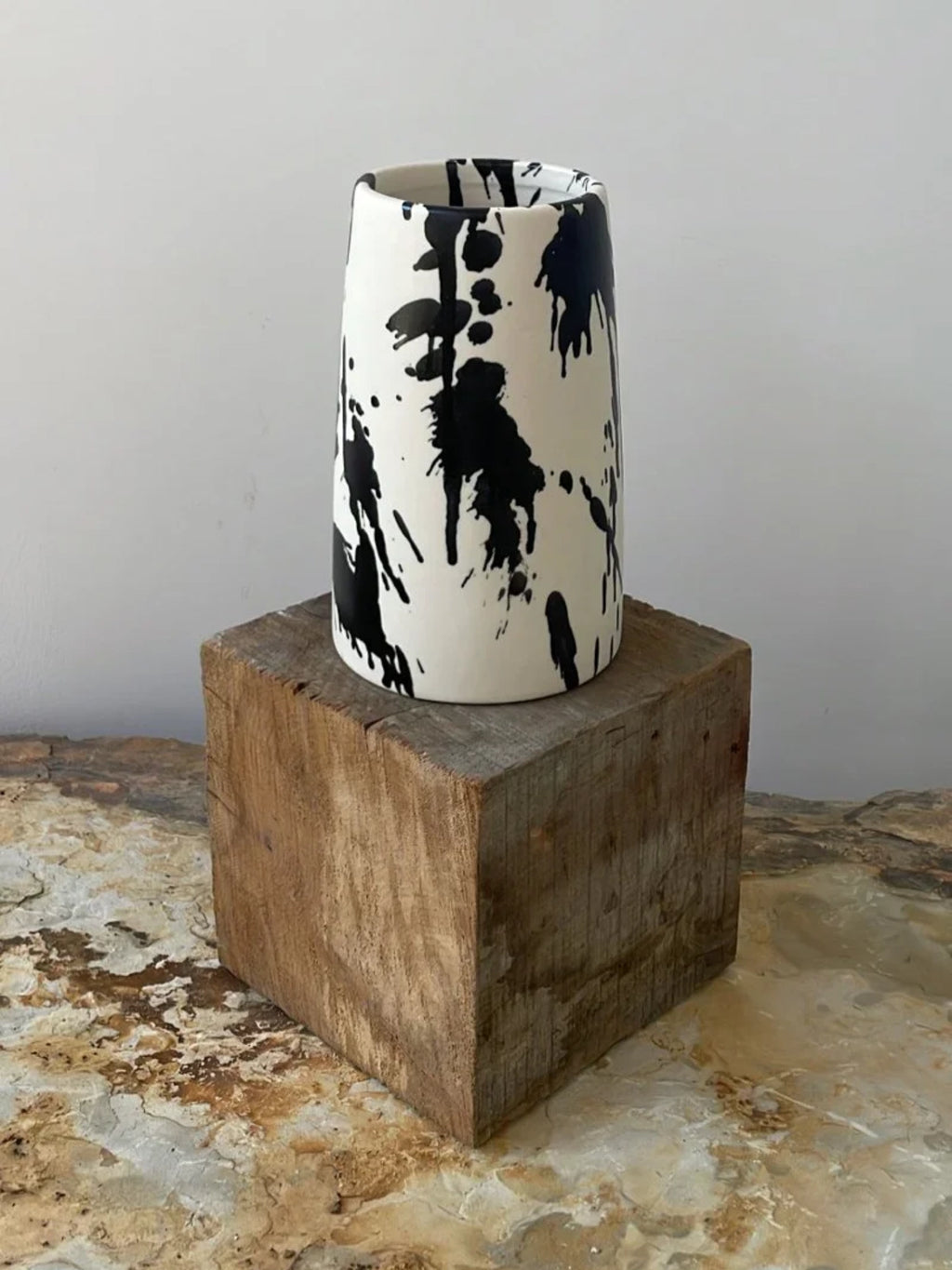 OWO Ceramics x That Cool Living Rock Vase II, a handcrafted ceramic vase with a tapered silhouette, features a white glaze artfully splattered with random black ink drips. This modern and stylish vase makes a bold statement for any minimalist or contemporary home.