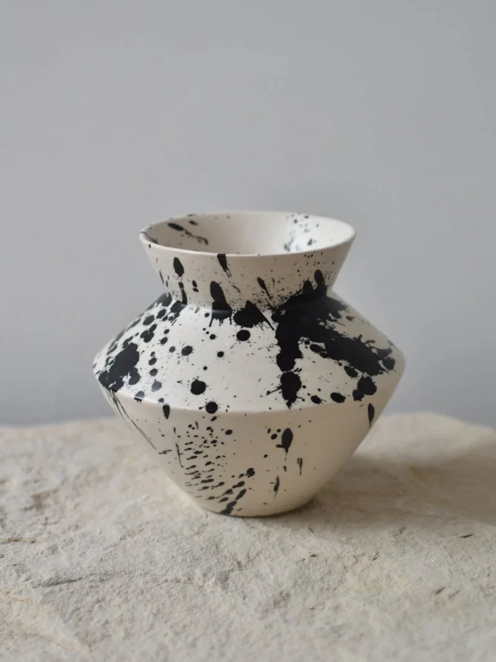 OWO Ceramics x That Cool Living Rock Vase I, a handcrafted ceramic vase with a modern geometric shape and a unique black splatter glaze. This stylish and elegant vase adds a touch of artistic flair to any home. Perfect for displaying fresh flowers or as a standalone decorative piece for individuals seeking unique, high-quality home decor.