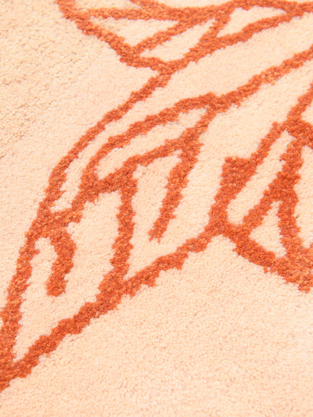 Haus Üger Shape of a Break Rug, a contemporary hand-tufted rug featuring a soft peach base with a bold, abstract organic pattern in warm terracotta and rust tones. This plush, textured wool blend rug provides a cozy feel and modern graphic appeal. Ideal for adding a touch of organic modern style to living rooms, bohemian bedrooms, or creative kids' rooms.