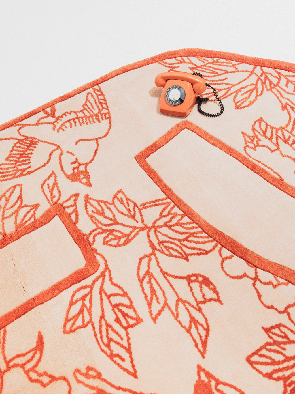 Haus Üger Shape of a Break Rug, a captivating organic modern area rug with a unique irregular silhouette, featuring a soft cream-colored ground and a plush, high-low pile texture. Vibrant terracotta orange tufted lines create an abstract floral and leaf pattern, defining the rug's distinct shape and adding a playful, contemporary touch. This designer accent rug is perfect for grounding a chic living room, bedroom, or creative studio space.