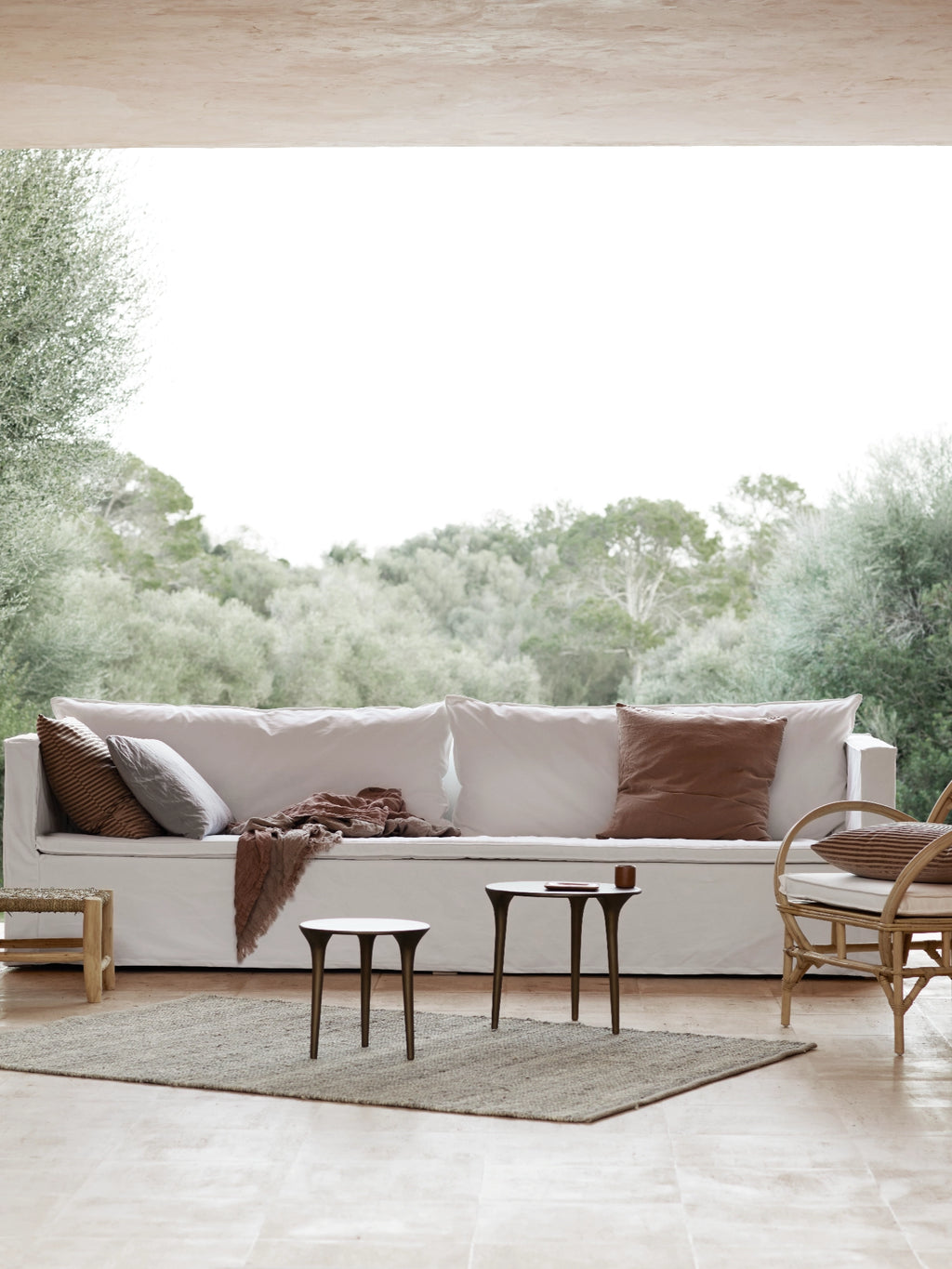 Tine K Feel Recycled Aluminium Table, a contemporary minimalist side table featuring a sleek round white tabletop and three elegantly curved, sculptural matte dark bronze recycled aluminum legs. This organic modern accent table is perfect for a living room, bedroom, or as a stylish small coffee table in Scandinavian or coastal-inspired spaces.
