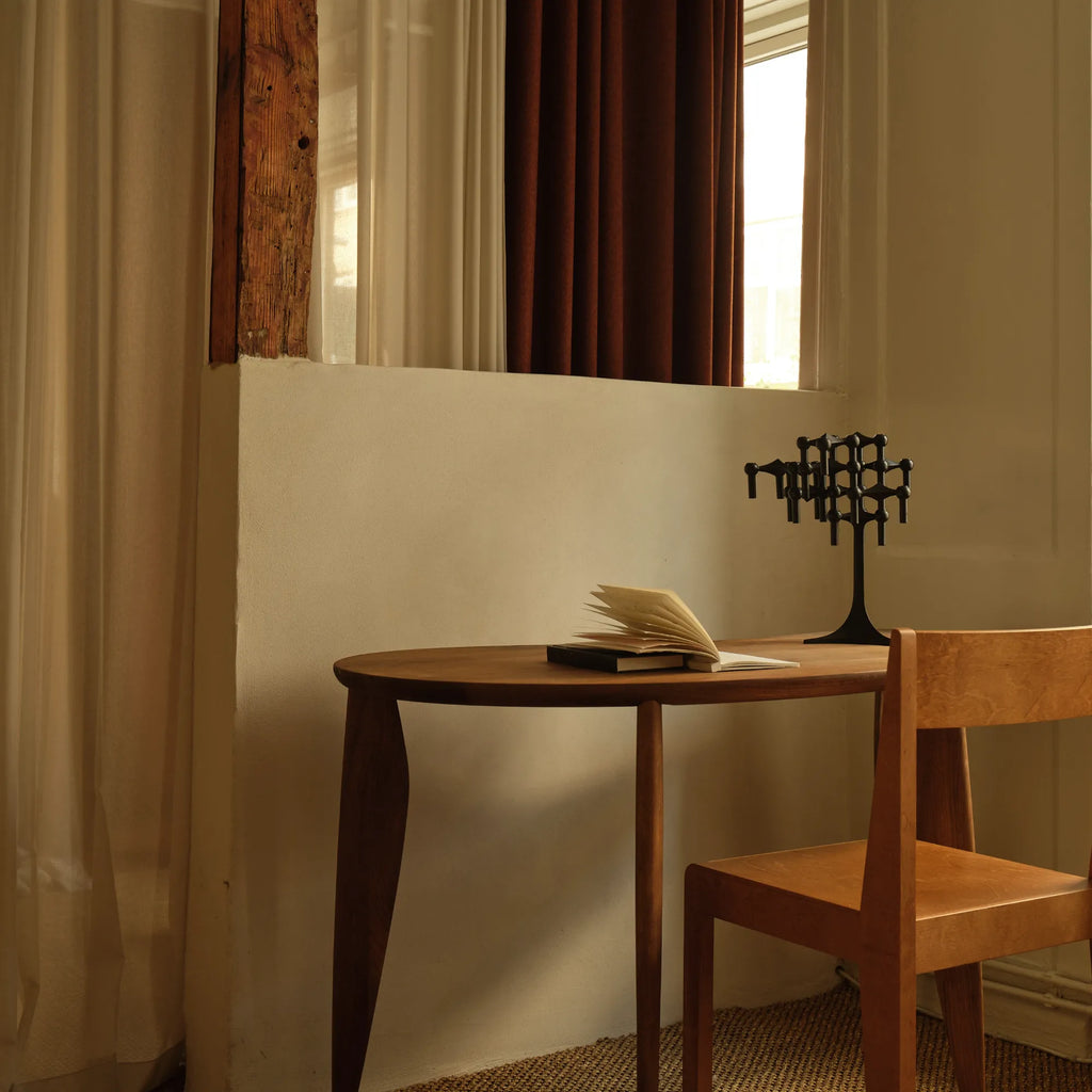 Stoff Nagel Candle Holder Stand, a matte black metal modular candelabra featuring an iconic interlocking geometric design and a sculptural, brutalist aesthetic. Its striking contemporary form allows for custom arrangements, making it a versatile piece of table decor or shelf styling. Ideal for mid-century modern living rooms, minimalist dining tables, or industrial chic spaces.
