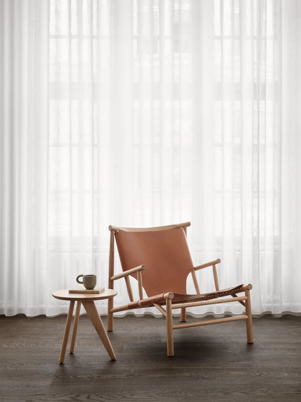 NORR11 Samurai Chair, a modern lounge chair with a warm cognac leather seat and durable light oak wood frame. This elegant, handcrafted chair is perfect for creating a stylish and comfortable reading nook in your contemporary living space.