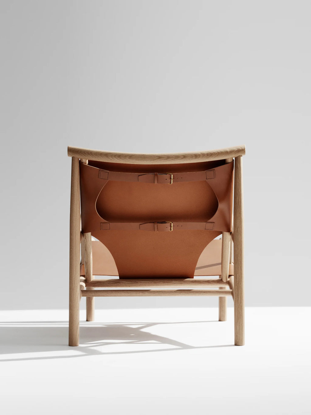 NORR11 Samurai Chair, a modern lounge chair featuring a natural wood frame and premium tan leather sling seat with adjustable buckle straps. This stylish chair offers elegant comfort for discerning homeowners seeking handcrafted quality.