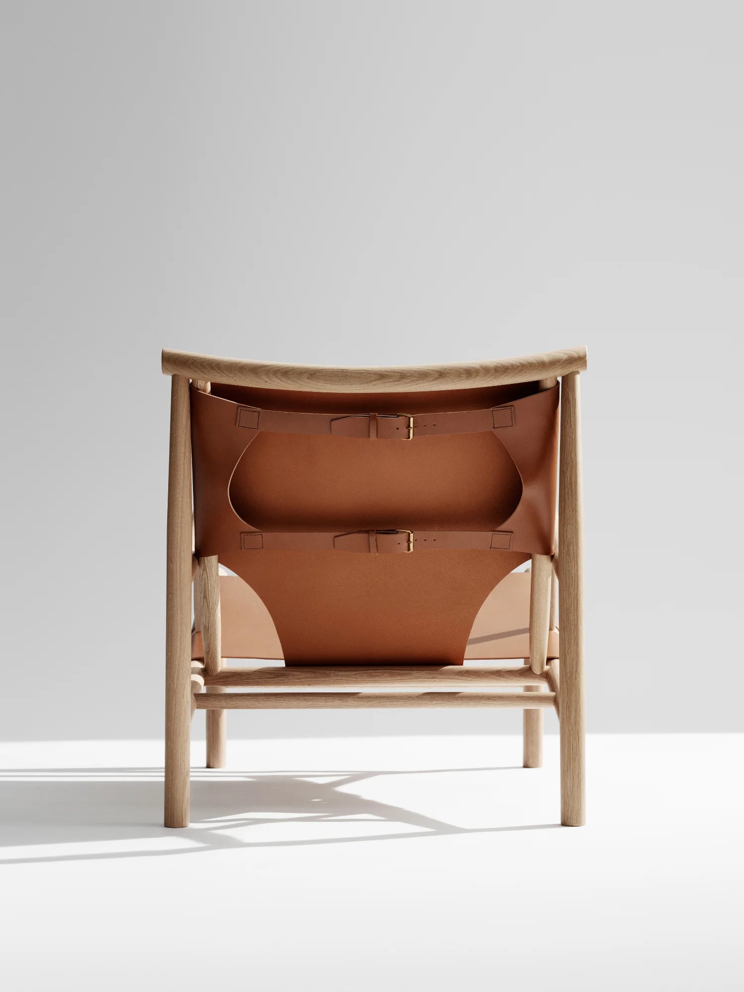 NORR11 Samurai Chair, a modern lounge chair featuring a natural wood frame and premium tan leather sling seat with adjustable buckle straps. This stylish chair offers elegant comfort for discerning homeowners seeking handcrafted quality.